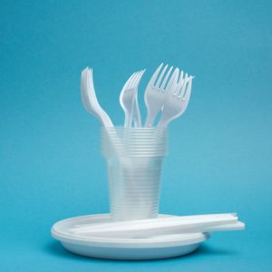 disposable plastic tableware plates, cups, forks and knives on a blue background, picnic set